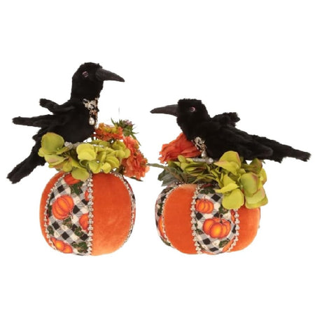 2 faux pumpkins with crows sitting on top of them.