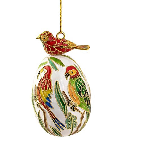 white egg shaped ornament with tropical birds on the sides and a red bird perched on top of the egg. Gold filagree outlines of all birds. Gold chord hanger.