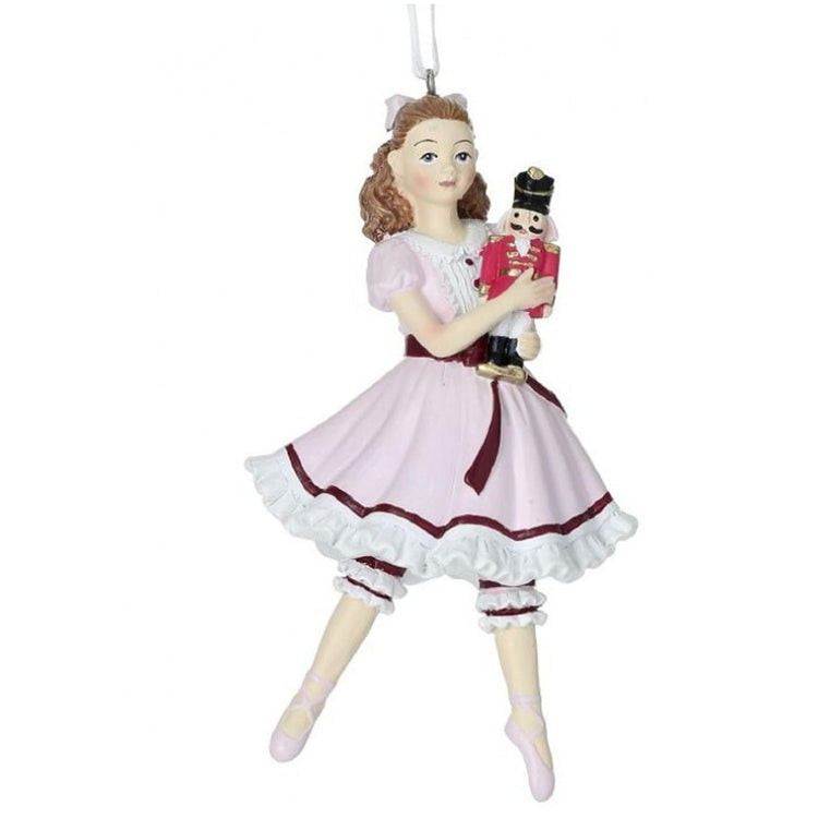 clara ballerina holding a nutcracker. She wears a pink dress with twhite ruffles and a bow in her hair