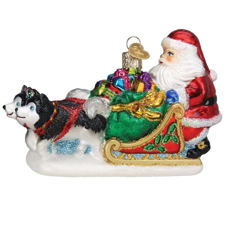 Blown Glass ornament of Santa pushing a sled full of toys, hauled by two huskies.