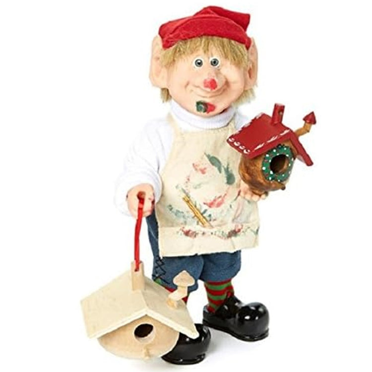 Standing elf figure. He is holding birdhouses. He has paint on his nose and on his apron.  Red stocking cap.