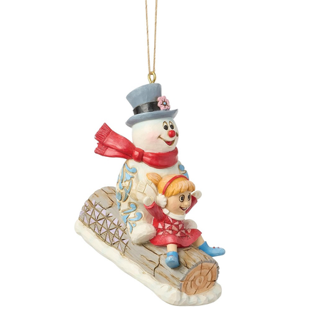 Christmas ornament of a snowman with a girl on a log sled against a white background