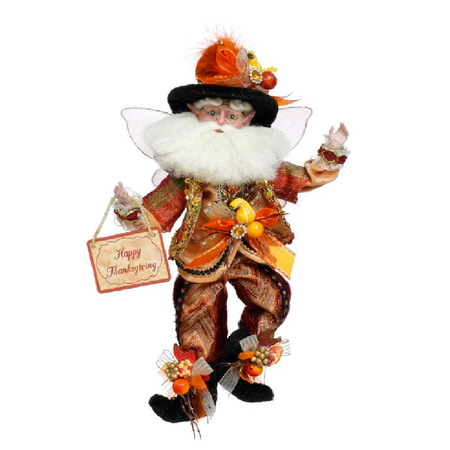 Bearded fairy wearing orange suit and hat with squash and pumpkin embellishments, holding a sign that says Happy Thanksgiving.