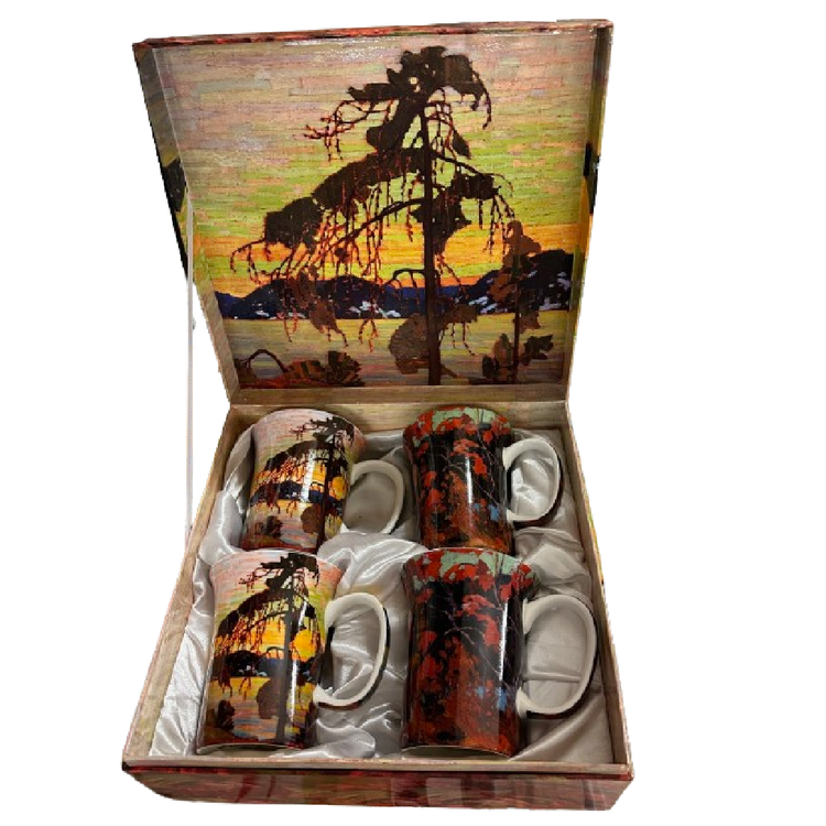 4 mugs in a matching gift box, two mugs have jack pine design and two autumn foliage.