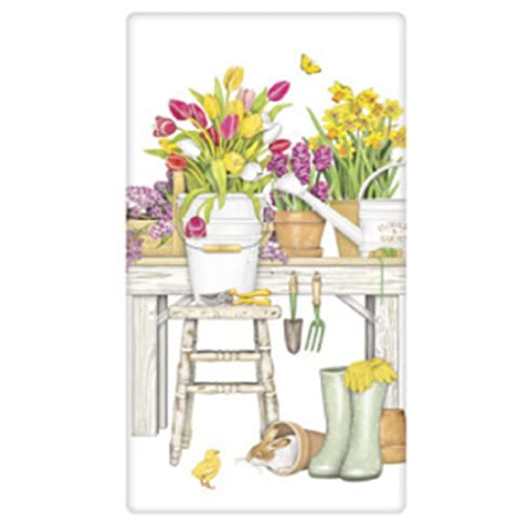 White towel with a garden bench, stool and tulips in pots on the bench. Hanging gardening towels, a chick and bunny and rainboots