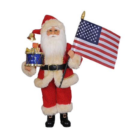 santa figurine in classic red suit, holding a snare drum with blocks spelling USA stacked on top, and an american flag in the other hand.