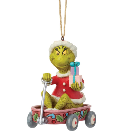 A Grinch Christmas ornament depicting the Grinch in a red Santa suit sitting in a pink decorated wagon and holding a gift box, hanging by a twine string against a white background.