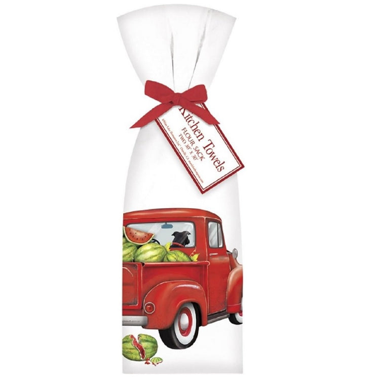 two white flour sack towels with a design of a red truck with watermelons in the bed, tied together with a red ribbon.