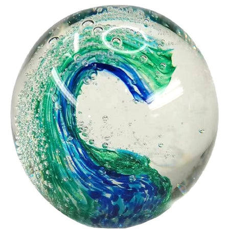 glass ball shaped paperweight with blue and green wave design inside.