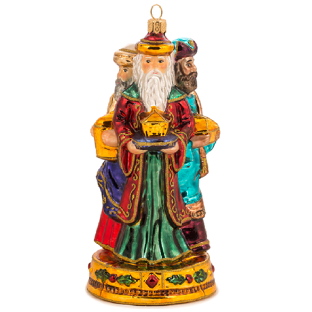 Blown glass ornament of three wise men with gifts on a pedestal.