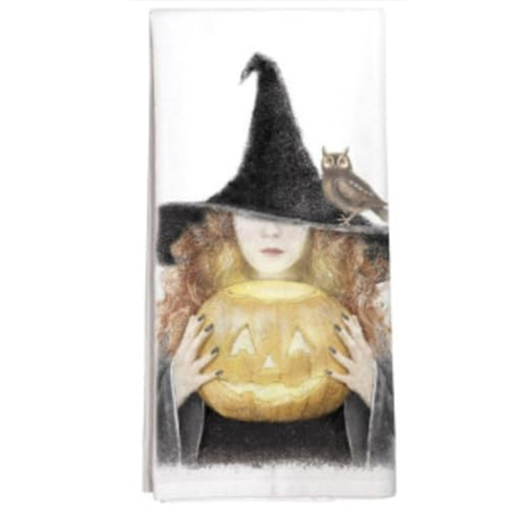 Witch holding a pumpkin design on white kitchen towel. There is an owl resting on the hat brim.