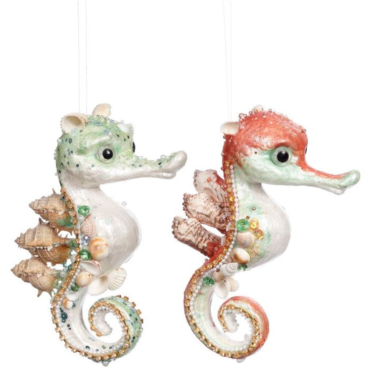 Two foam, beaded seahorse ornaments, one coral pink, one light green. both are decorated with lots of natural shells.