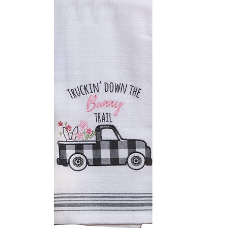 Folded white kitchen towel.  Embroidered text says "Truckin' Down the bunny Trail.  Has a black and white checks pickup truck. Flowers and the top of a bunny head showing ears with flowers.