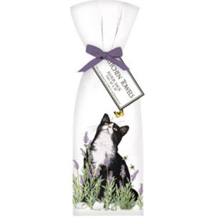 White towel with a bow tide on top and a tag that says Kitchen Towels. Print shows a black and white cat looking up at a yellow butterfly, standing in lavender flowers.