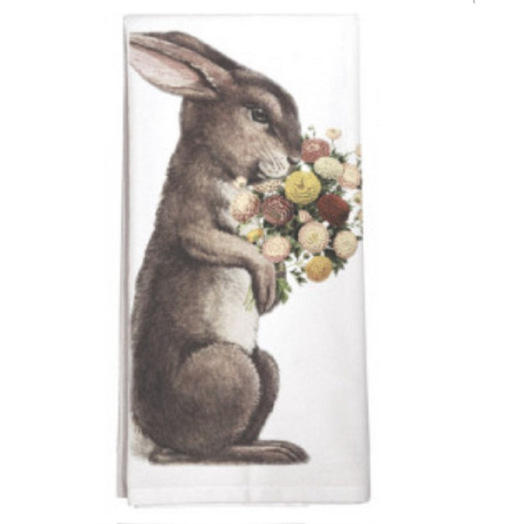White kitchen towel shows a brown bunny sitting on his hind legs. He is smelling a bouquet of flowers he is holding. 