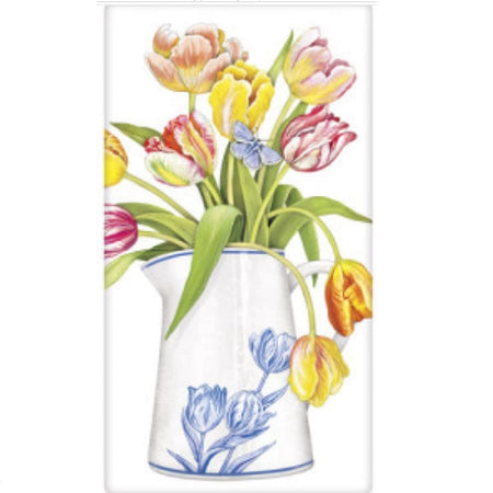White towel with white pitcher of tulips.  The pitcher is also white with a blue floral design.  The tulips are shades of yellow , pink and red with a single blue butterfly.