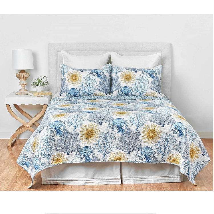 Bed with the Monterey Mist Quilt on it. The quilt is off white with a blue coral pattern and gold coral accent.  2 Matching Shams.