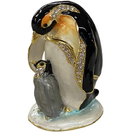 Jeweled box shaped as a father penguin and a baby at his feet. The baby is grey and black. The father is black and white with tan accent. They stand on a white base and have cyrstal accents.