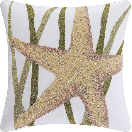 White pillow with a tan starfish and background of green seagrass
