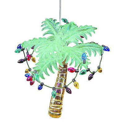 Glass palm tree ornament with green palm leaves, gold trunk & a string of multi color lights around the tree.