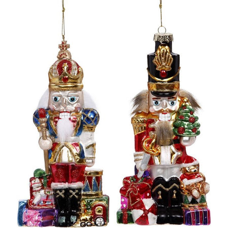 2 blown glass nutcracker ornaments, one has white hair and beard the otehr has brown, both are surrounded by gifts.