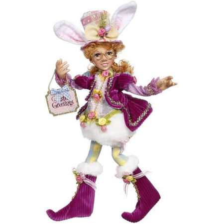 Elfin girl wearing top hat with bunny ears, purple velvet  jacket and boots. Holding a sign that says "Easter greetings"