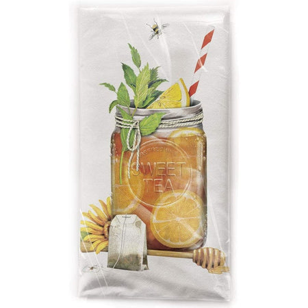 Folded white kitchen towel showing a glass of iced tea, the glass it a ball jar. There is lemon and mint and a straw in the tea and a tea bag and honey dipper next to the jar.
