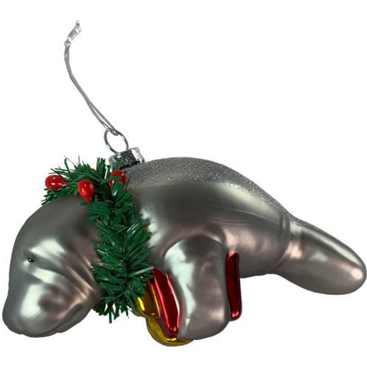Grey manatee holding a red gift, a wreath around its neck, and a glittery back.