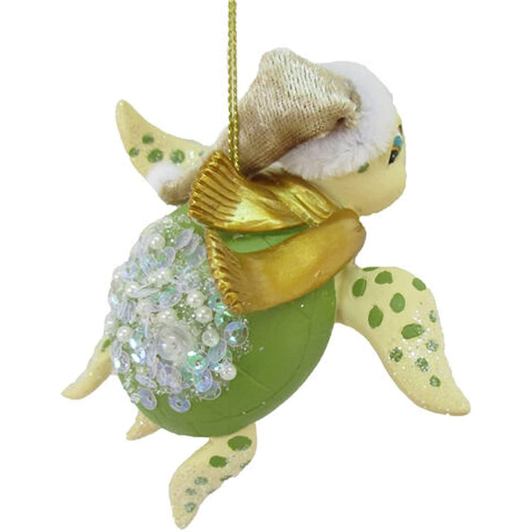 Resin green turtle ornament with iridescent sequin accents, gold scarf and stocking cap.