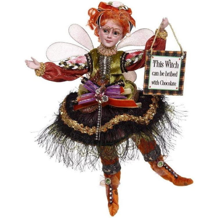 Young girl fairy with orange boots, green top and black feathery skirt, holding a sign that says "this witch can be bribed with chocolate"