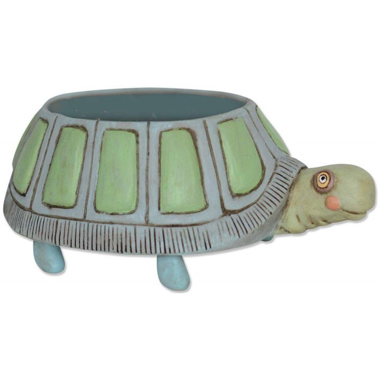 Turtle design round planter. The turtle is painted in shades of green, blue and gray. The plant sits in the shell.