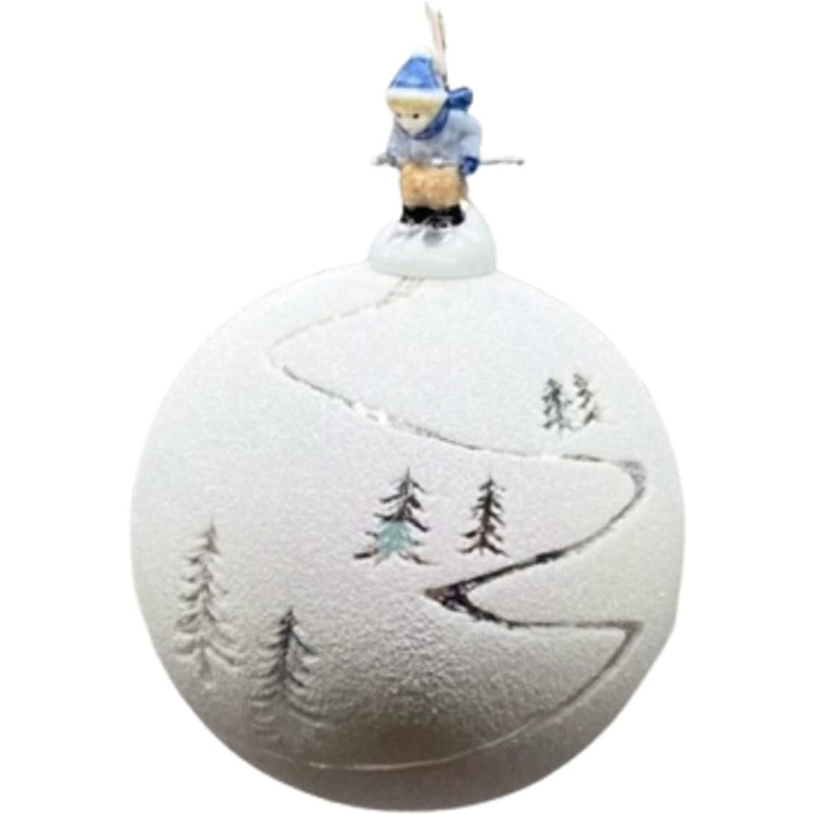 Blown glass ornament coated in white glitter to look like snow, with silver trees and ski tracks. Topped with little skiier.