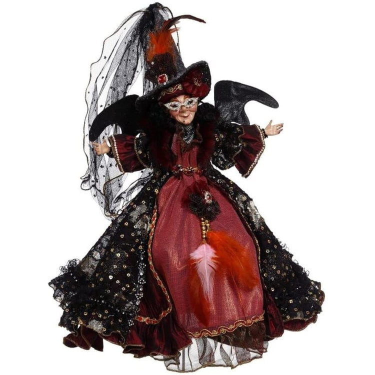 Witch wearing long red and black dress, tall witch hat with veil and red feather.