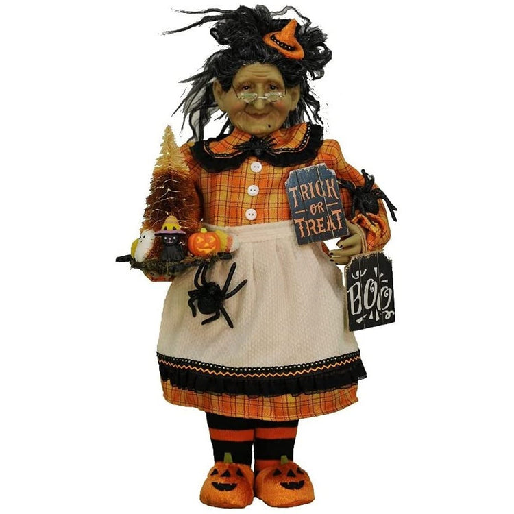 Old witch with an orange, yellow & black outfit & white apron.