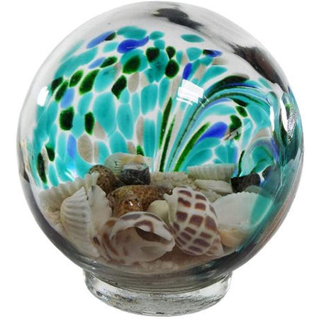 Glass globe with sand & shells inside of it.