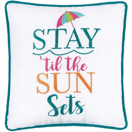 White pillow that says stay 'til the sun sets with a beach umbrella on it.