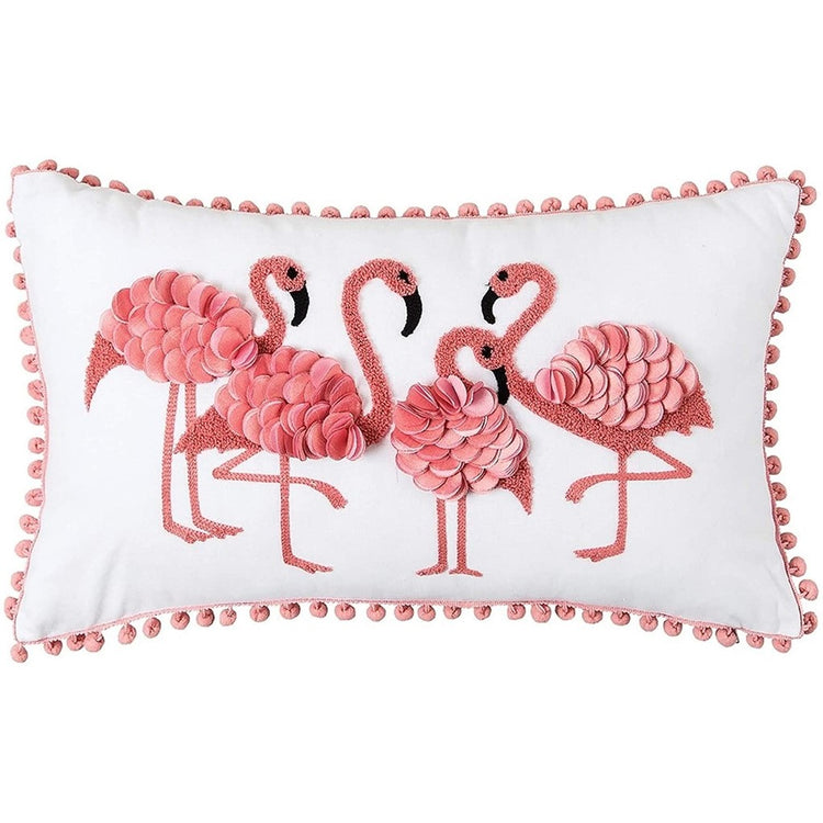 rectangular white throw pillow with pink pompom accents around edge & four pink flamingos in center of pillow.