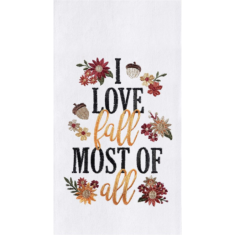 White flour sack towel with the words "I love fall most of all" embroidered on it, along with fall flowers and acorns,