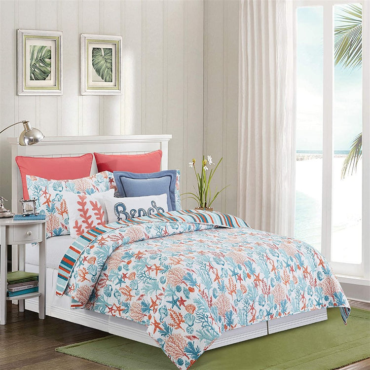 queen size bed with a white quilt with orange and blue shells, starfish and coral pattern, and matching pillows.
