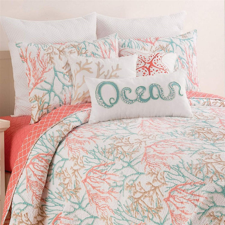 Close up top of bed with white bed spread with brown, teal & orange coral. Bed has matching pillows & pillow text "Ocean"
