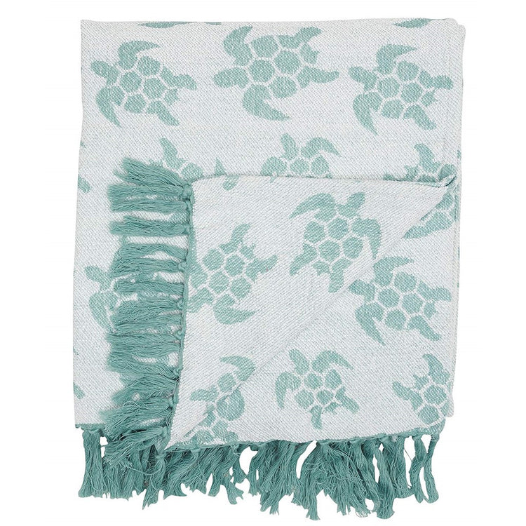 Throw blanket in shades of green with sea turtle print and fringe.