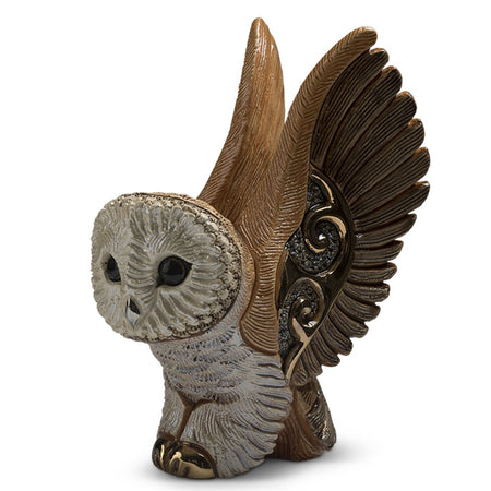 Owl shaped figurine facing front with wings spread high overhead. Tans and browns with gold accent.