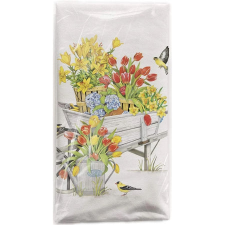 White cotton flour sack towel with a printed image of a wheel barrow full of yellow lilies and daffodils, red tulips and a potted hydrangea.