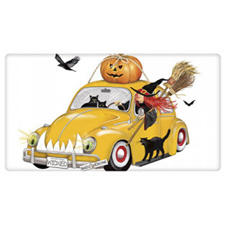 white towel with a red headed witch driving an orange Volkswagen bug with a pumpkin on top.