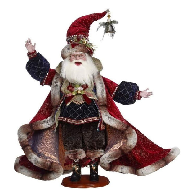 Santa figurine on a stand.  He wears a long red coat with fur trim and green puff sleeves.  He has a tall pointy hat, same fur trim and a bell that hangs from the end.