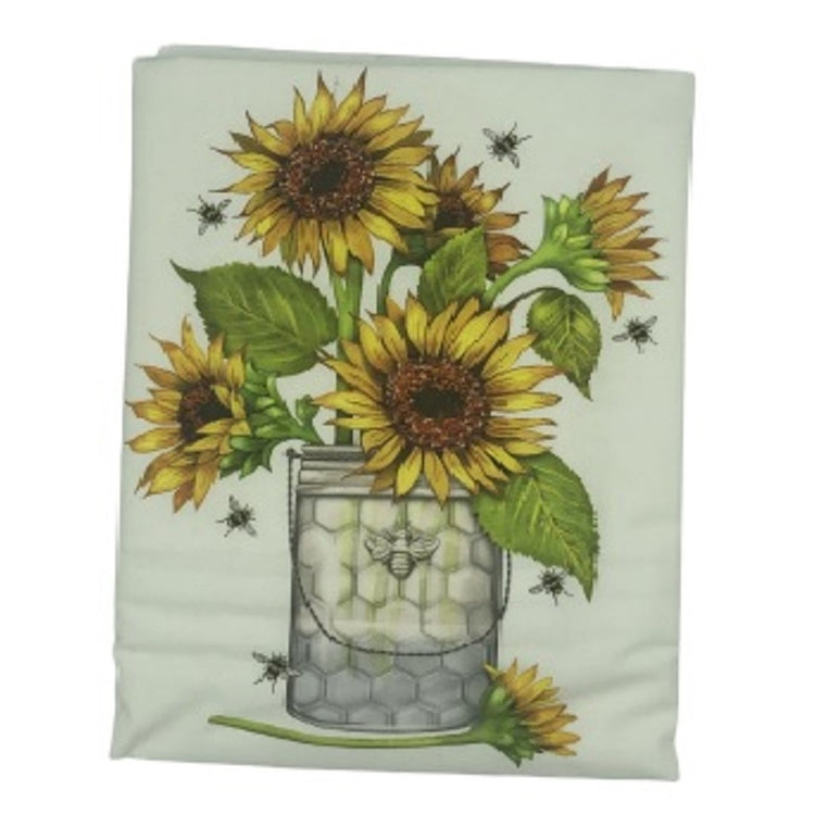 white flour sack towel with a glass container of sunflowers and bees flying around.