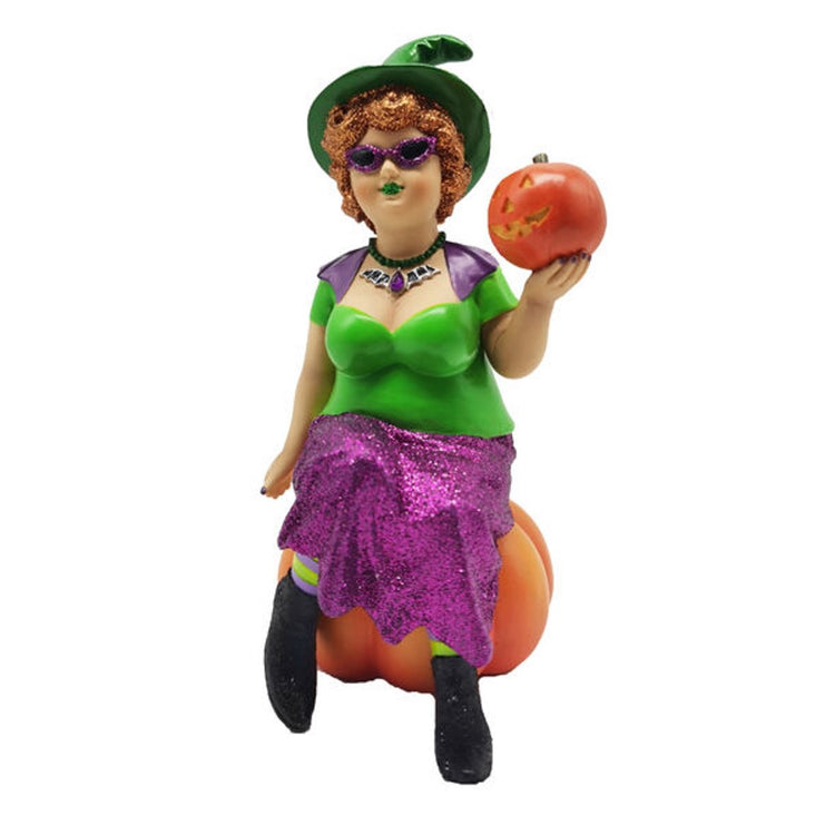 Witch with short orange hair wearing a green top and purple glittery skirt. She's sitting on a large pumpkin and holding a jack o lantern.