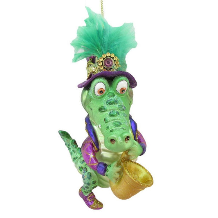 Figurine ornament shaped like an alligator blowing a saxophone.  Green hat with embellishments, purple jacket.