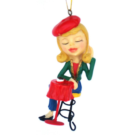 ornament show blond girl wearing a red beret, green jacket, blue slacks sitting at a small table