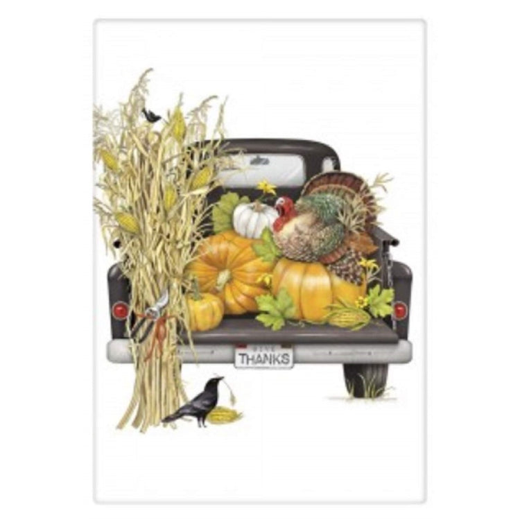 White flour sack kitchen towel with print of  black truck with pumpkins and turkey.